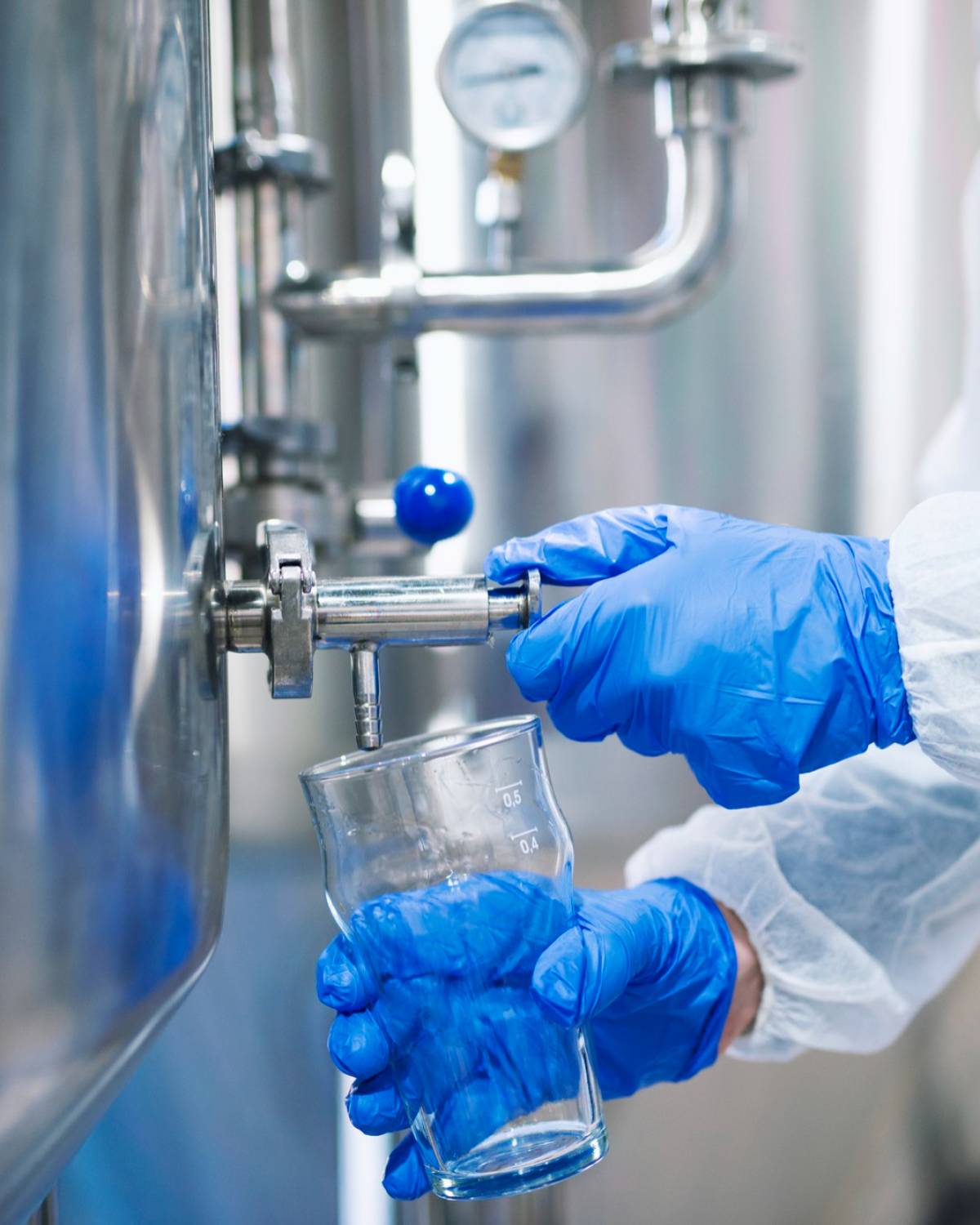 close-up-view-hands-protective-gloves-opening-tap-valve-filling-glass-with-samples-from-industrial-machine-reservoir